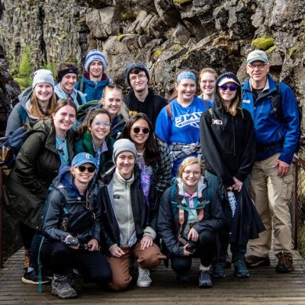 A group of U N E students taking a photo together in a rocky and mossy gorge